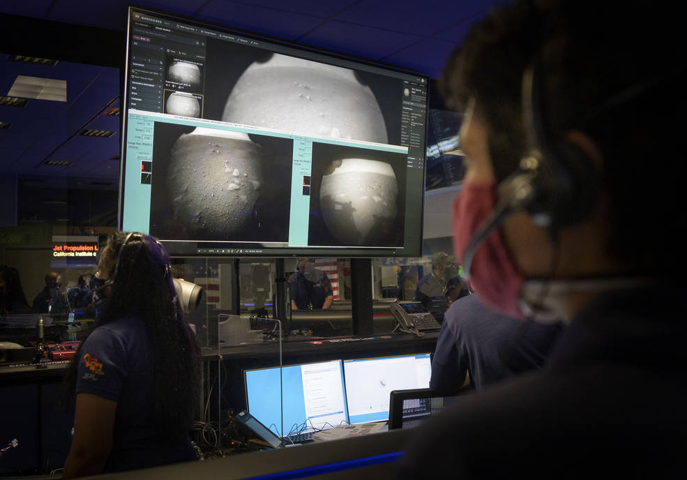 Members of NASA’s Perseverance Mars rover team watch in mission control as the first images arrive moments after the spacecraft successfully touched down on Mars, Thursday, Feb. 18, 2021, at NASA's Jet Propulsion Laboratory in Pasadena, California. A key objective for Perseverance’s mission on Mars is astrobiology, including the search for signs of ancient microbial life. The rover will characterize the planet’s geology and past climate, pave the way for human exploration of the Red Planet, and be the first mission to collect and cache Martian rock and regolith. Credits: NASA/Bill Ingalls