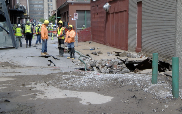 St. Louis City Water workers inspect the damage from a rupture water main that exploded on Tuesday Morning in Downtown St. Louis, flooding garages and basements of nearby businesses.
