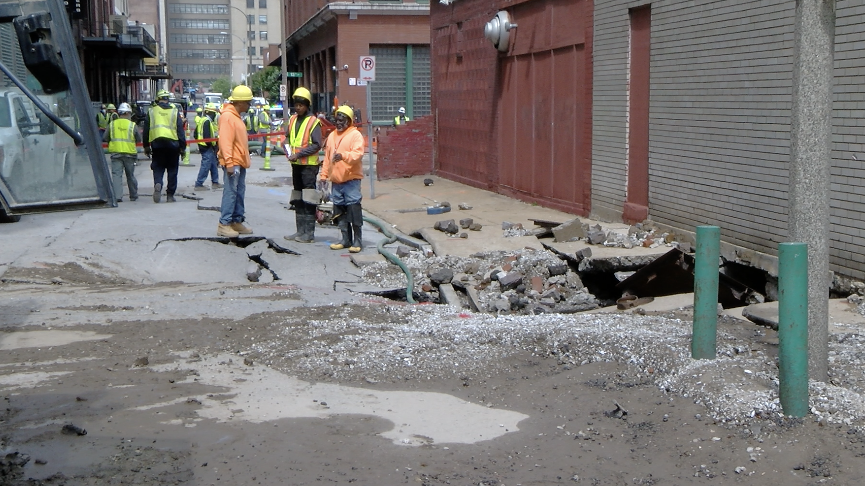 St. Louis City Water workers inspect the damage from a rupture water main that exploded on Tuesday Morning in Downtown St. Louis, flooding garages and basements of nearby businesses.